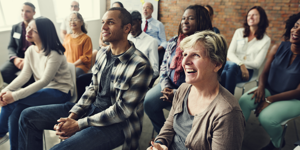 A group of diverse people listening to a speaker at a training session.