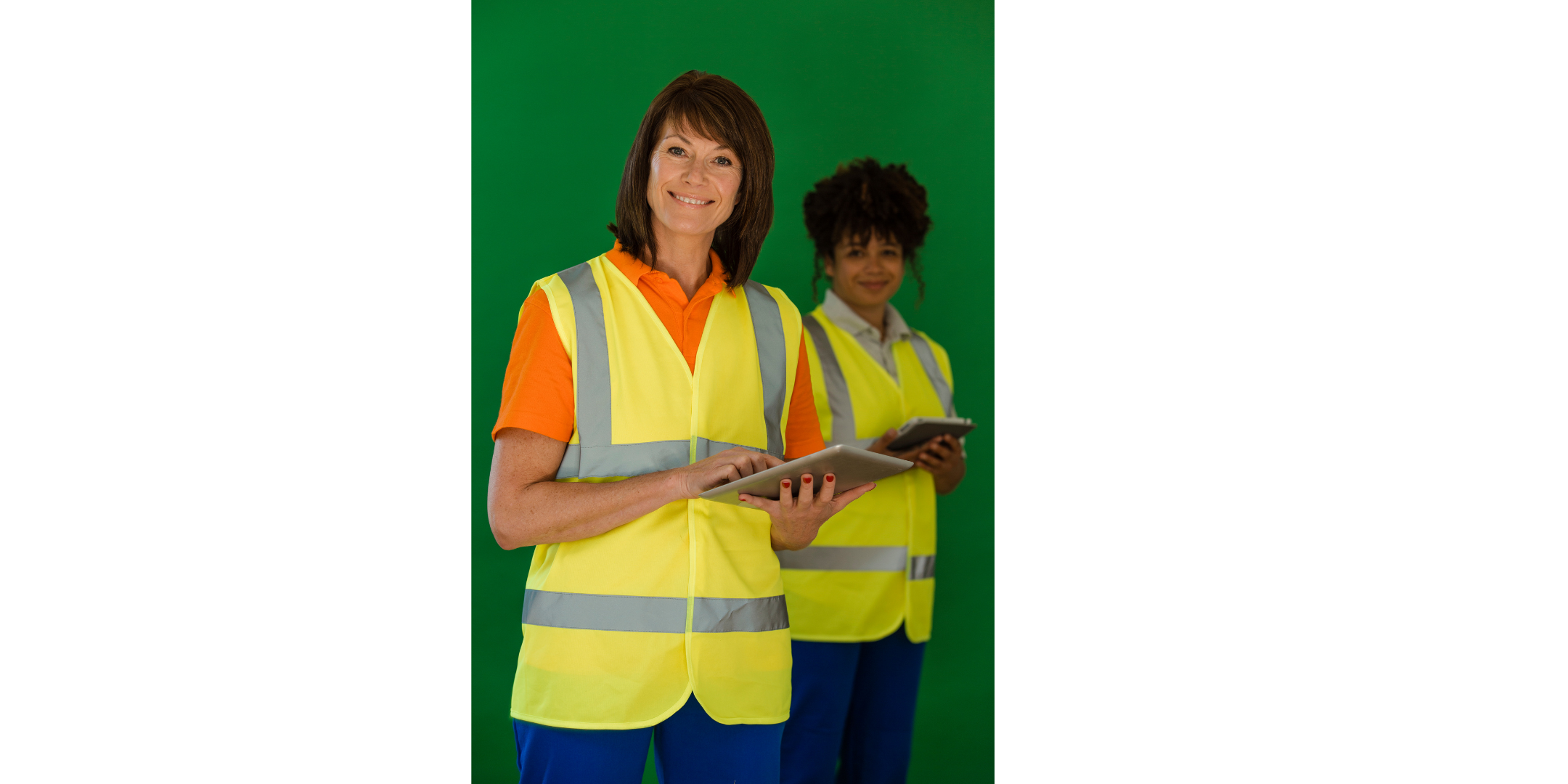Two women with clipboards. Both wearing high vis vests and smiling.